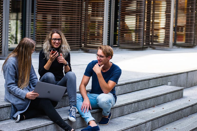 Three Persons Sitting on the Stairs Talking With Each Other